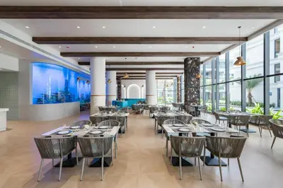 a dining room with tables and chairs and windows at Sunshine Beach Appartments, 2BD in Layan Beach