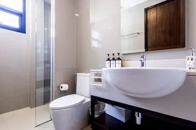 a white bathroom with a toilet and a sink at Villa Laguna Park in Ban Thalat Choeng Thale
