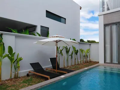 an umbrella and chairs next to a swimming pool at Golden Andes \u8c6a\u534e\u5ea6\u5047\u522b\u5885 in Ban Mut Dok Khao