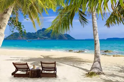two chairs and a table on a beach with palm trees at The Title Legendary D-605 1 BR Bangtao Beach in Bang Tao Beach