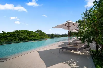 a swimming pool with chairs and an umbrella at Beachside by Villacarte in Bang Tao Beach