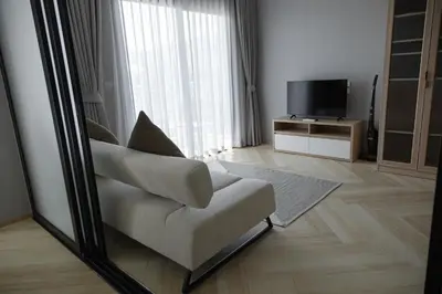 a living room with a chair and a television at The Legendary Bang Tao 1-bedroom apart #711 in Bang Tao Beach