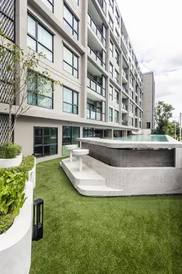 an exterior view of a building with a green yard at The SPACE Apartment 612 in Ban Thalat Choeng Thale