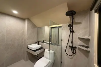a bathroom with a shower and a toilet and a sink at Sand Maré Karon Hotel in Karon Beach