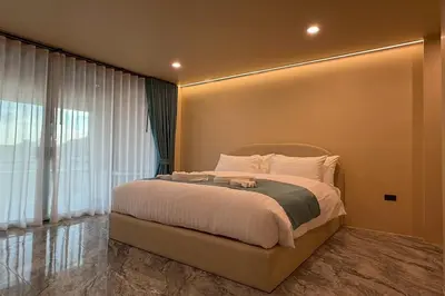 a bedroom with a bed and a large window at Sand Maré Karon Hotel in Karon Beach