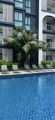a swimming pool in front of a building at Sun Sea Sand in Thalang