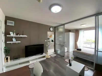 a living room with a flat screen tv and a bedroom at Nassaree Condo in Phuket Town