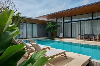a swimming pool with chairs and a house at Botanica Four Seasons Bang Tao by My Home Phuket in Ban Na Sok