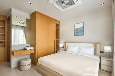 a bedroom with a white bed and a wooden cabinet at Botanica Four Seasons Bang Tao by My Home Phuket in Ban Na Sok