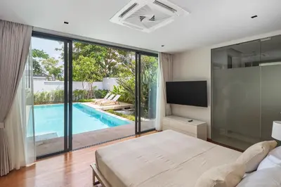 a bedroom with a bed and a swimming pool at Botanica Four Seasons Bang Tao by My Home Phuket in Ban Na Sok