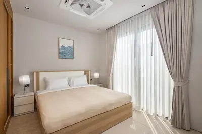 a bedroom with a bed and a large window at Botanica Four Seasons Bang Tao by My Home Phuket in Ban Na Sok
