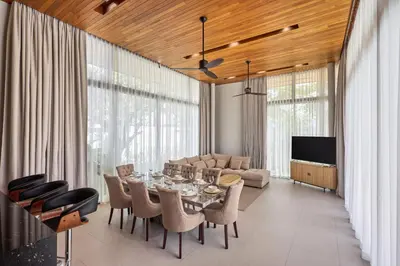 a dining room with a table and chairs and a couch at Botanica Four Seasons Bang Tao by My Home Phuket in Ban Na Sok