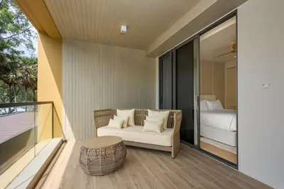 a room with a balcony with a bed and a chair at Laguna BeachSide Bang Tao by My Home Phuket in Bang Tao Beach