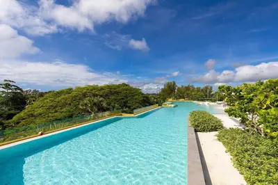 a large swimming pool with blue water and trees at Laguna BeachSide Bang Tao by My Home Phuket in Bang Tao Beach