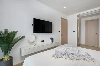 a white bedroom with a flat screen tv on the wall at Ozone condominium Bang Tao by My Home Phuket in Laguna Phuket