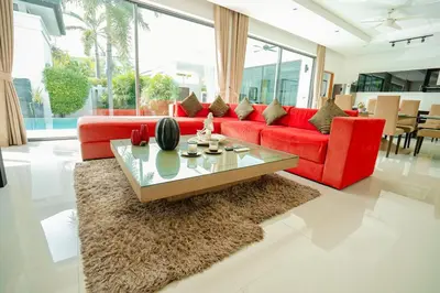 a living room with a red couch and a table at Villa Heaven - Peaceful 3 Bedroom Private Pool Villa in Ban Kata
