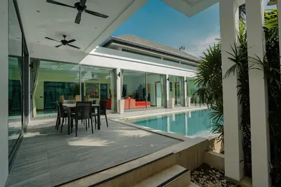 a patio with a table and chairs next to a swimming pool at Villa Heaven - Peaceful 3 Bedroom Private Pool Villa in Ban Kata