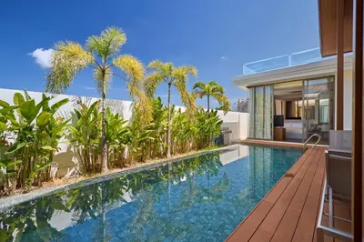 an infinity pool with palm trees and a house at Villa the Ozone Bang Tao by My Home Phuket in Laguna Phuket