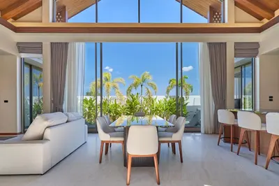 a dining room with a table and chairs and large windows at Villa the Ozone Bang Tao by My Home Phuket in Laguna Phuket