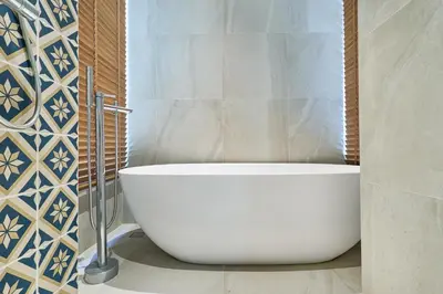a white tub in a bathroom with blue and white tiles at Villa the Ozone Bang Tao by My Home Phuket in Laguna Phuket