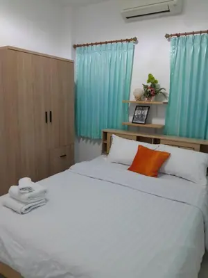 a bedroom with a large white bed with blue curtains at Baan Saun PK in Ban Bang La