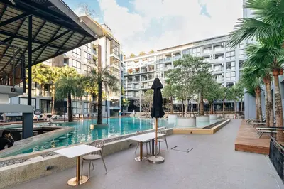 a swimming pool with chairs and an umbrella next to a building at C255 Best Stay Experience Condo with Full Facilities in Kamala Beach