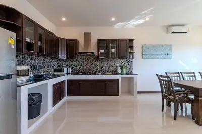 a kitchen with wooden cabinets and a table with chairs at V274 Prime Location Large Terrace Pool View BBQ in Ban Saiyuan (1)