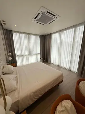 a bedroom with a large bed with white sheets and windows at Pride luxury house in Koh Lone