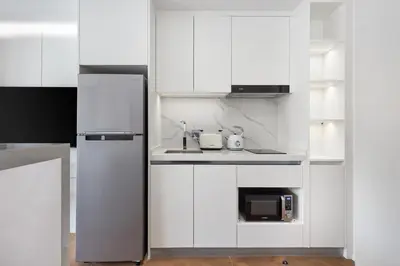 a white kitchen with a refrigerator and a microwave at Sunshine Beach Bang Tao by My Home Phuket in Layan Beach