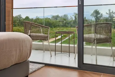 a bedroom with a bed and two chairs on a balcony at Sunshine Beach Bang Tao by My Home Phuket in Layan Beach