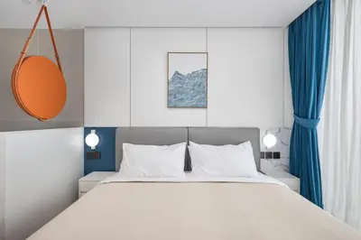 a bedroom with a large white bed with blue curtains at Sunshine Beach Bang Tao by My Home Phuket in Layan Beach