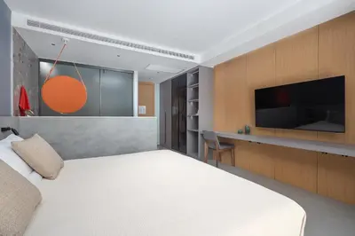 a bedroom with a white bed and a flat screen tv at Sunshine Beach Bang Tao by My Home Phuket in Layan Beach