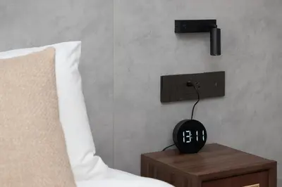 a black alarm clock on a night stand next to a bed at Sunshine Beach Bang Tao by My Home Phuket in Layan Beach