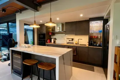 a kitchen with a counter with stools in it at RIVERHOUSE Solar-Powered Luxury Pool Villas in Laguna Phuket