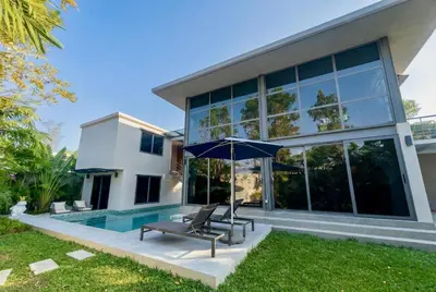 a house with a pool and an umbrella at RIVERHOUSE Solar-Powered Luxury Pool Villas in Laguna Phuket