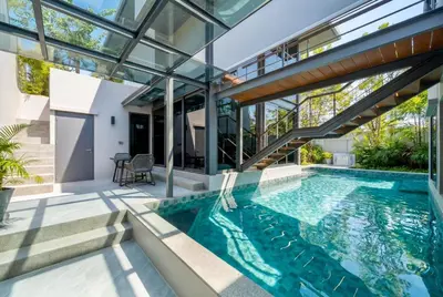 an indoor swimming pool in a house with glass walls at RIVERHOUSE Solar-Powered Luxury Pool Villas in Laguna Phuket
