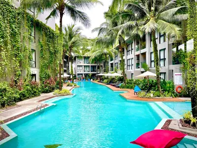 a swimming pool in a resort with palm trees at Diamond Resort 1 Bdr Bang Tao in Bang Tao Beach