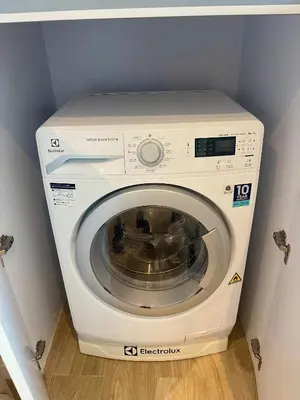 a white washing machine in a corner of a room at Diamond Resort 1 Bdr Bang Tao in Bang Tao Beach