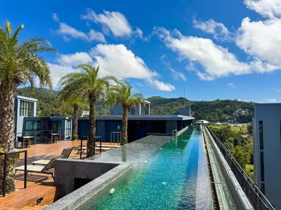 a swimming pool on the roof of a building with palm trees at Comfortable 1 bdr Kamala City Gate in Kamala Beach