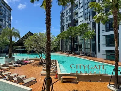 a swimming pool with chaise lounge chairs and palm trees at Comfortable 1 bdr Kamala City Gate in Kamala Beach