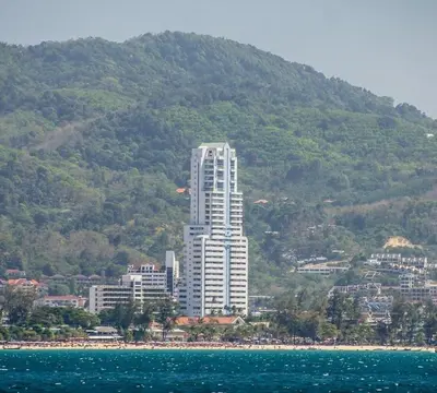a tall white building in front of a mountain at Highest Apartment in Phuket Panaromic Seaview in Patong Beach