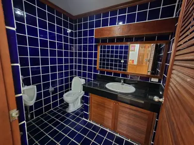 a blue tiled bathroom with a toilet and a sink at Villa Vasu in Ban Bang Khu