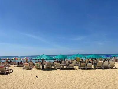a group of chairs and umbrellas on a beach at Karon Little House in Karon Beach