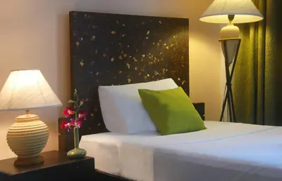 a bedroom with a bed with a green pillow and a lamp at PapaCrab Boutique Guesthouse in Kamala Beach