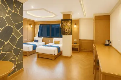 a hotel room with two beds and a table at Tiger Complex Inn in Patong Beach