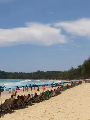 a line of chairs and umbrellas on a beach at Milos House in Phuket Town