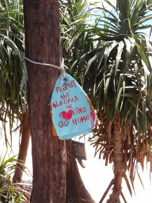 a sign attached to a tree with writing on it at Milos House in Phuket Town
