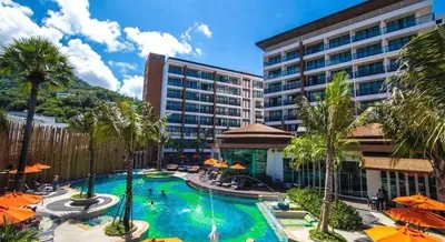 a pool with palm trees and umbrellas in a hotel at The Beach Condotel Kata in Kata Beach