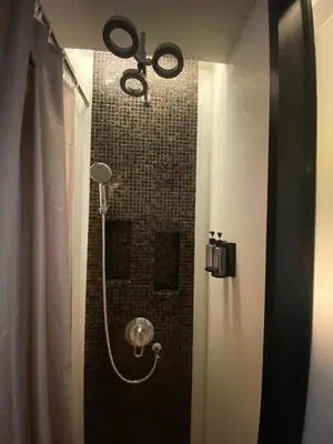 a bathroom with a shower with a shower head at The Beach Condotel Kata in Kata Beach