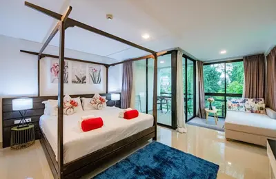 a bedroom with a canopy bed with red pillows at the Kris Bangtao Phuket not in laguna area in Laguna Phuket